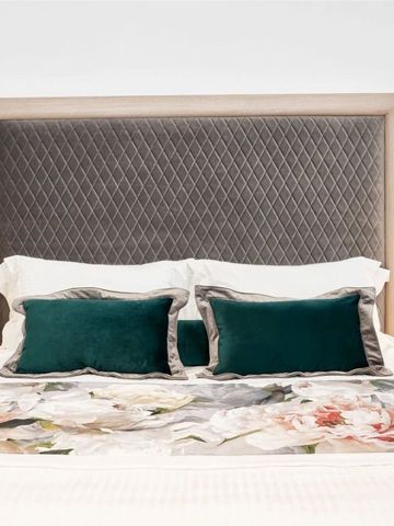 Luxuriöses Doppelbett mit feiner Bettwäsche und grünen Akzenten