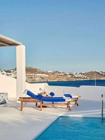 Sonnenliegen und Pool mit Panoramablick auf das glitzernde Meer von Mykonos
