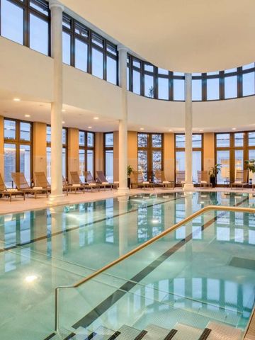 Beheizter Innenpool mit Liegestühlen und großen Fenstern im Spa-Bereich