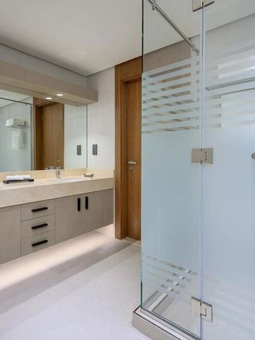 Modernes Badezimmer mit großem Spiegel und Duschbereich mit Glaswand.