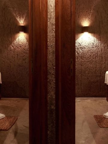 Warmer, stimmungsvoll beleuchteter Spa-Behandlungsraum mit Holzelementen