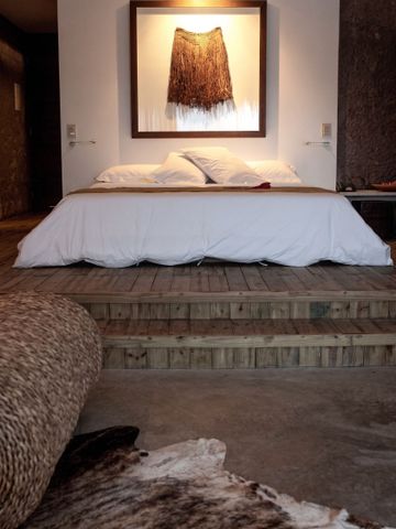 Schlafzimmer mit erhöhtem Bett und natürlichem Dekor
