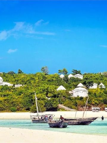 Traditionelle Boote im klaren Wasser vor grüner Küstenlandschaft