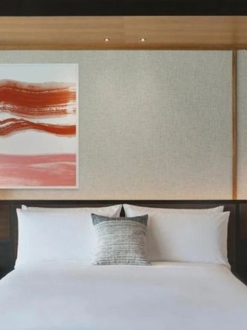 Modernes Hotelzimmer mit Kunstwerk über dem Bett und eleganter Beleuchtung