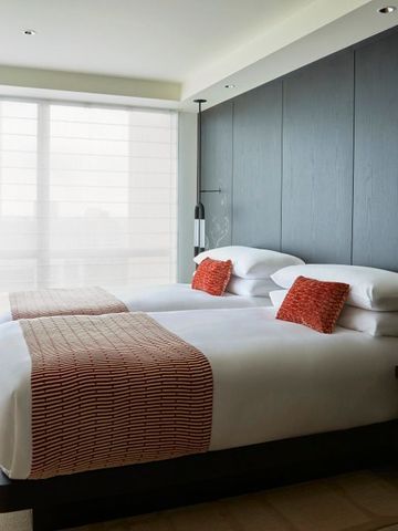 Modernes Hotelzimmer mit zwei Betten, großen Fenstern und stilvoller Einrichtung