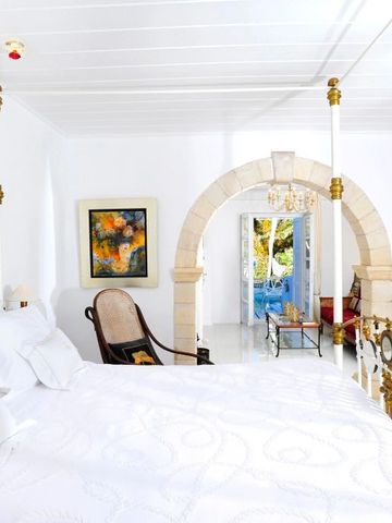 Luxuriöses Zimmer mit Bogenarchitektur, Kunstwerken und Zugang zu einem hellen Raum.