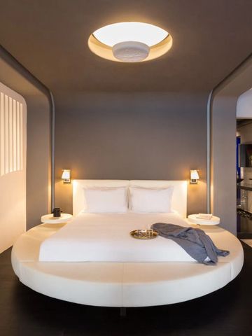 Zimmer mit rundem Bett und stilvollem Design in neutralen Farben