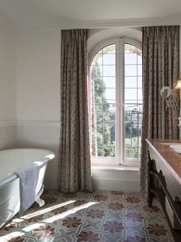 Helles Badezimmer mit großer Badewanne und Blick auf den Garten.