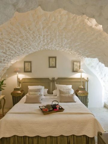 Gemütliches Schlafzimmer mit gewölbter Steinwand und Doppelbett im Landhausstil