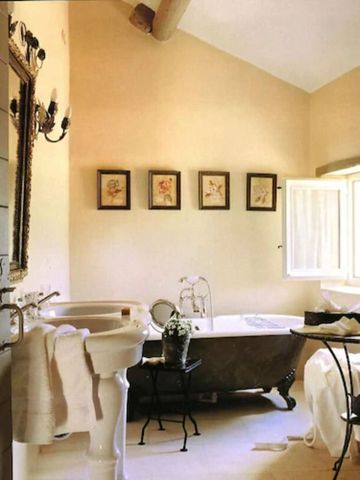 Helles Badezimmer mit freistehender Badewanne und Kunst an den Wänden