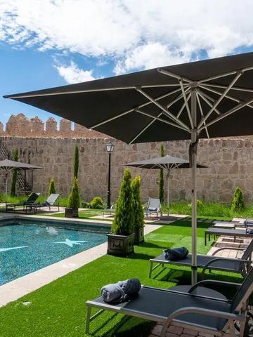 Sonnenliegen und Sonnenschirme am Pool mit Steinmauer im Hintergrund