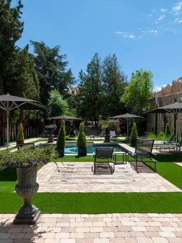Gartenansicht mit Pool und Liegestühlen umgeben von Bäumen und Mauern