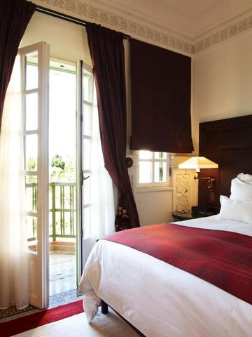 Einladendes Hotelzimmer mit Doppelbett und Balkon im warmen Licht.