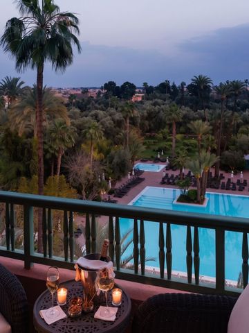Blick vom Balkon auf beleuchteten Pool und Palmen im Garten