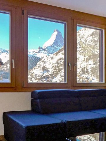 Wohnzimmer mit großen Fenstern und Blick auf ein schneebedecktes Bergpanorama