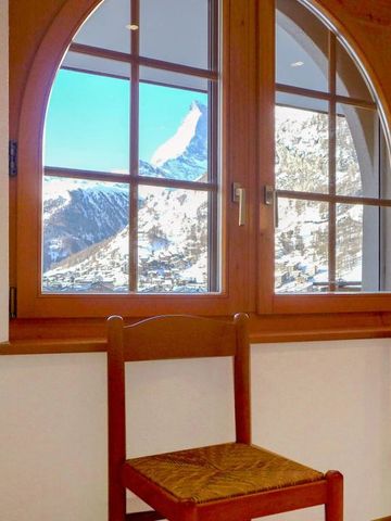 Fenster mit Rundbogenrahmen und Blick auf schneebedeckte Berge