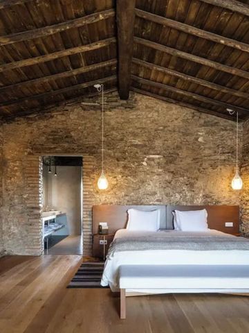 Rustikales Zimmer mit Natursteinwänden und Holzbalkendecke