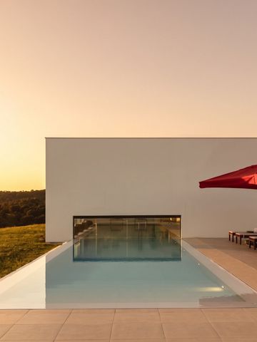 Infinity Pool mit Sonnenliegen und Sonnenschirmen bei Sonnenuntergang