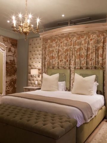 Geräumiges Schlafzimmer mit Kronleuchter und luxuriösem Bett