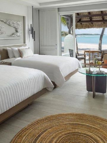 Helles Zimmer mit zwei Betten und Blick auf das Meer durch raumhohe Fenster