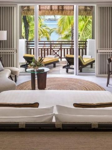 Zimmer mit modernem Design, Sitzecke und Terrasse mit Blick auf Palmen und Meer