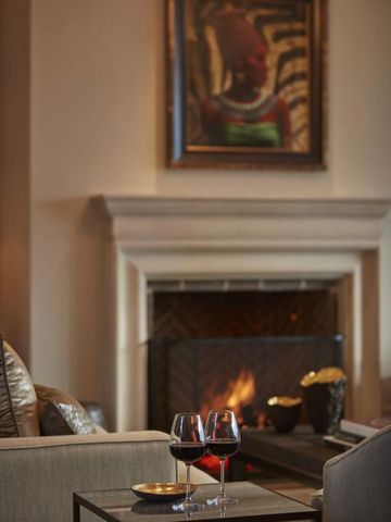 Gemütliche Lounge mit Kamin und zwei Gläsern Rotwein auf dem Tisch