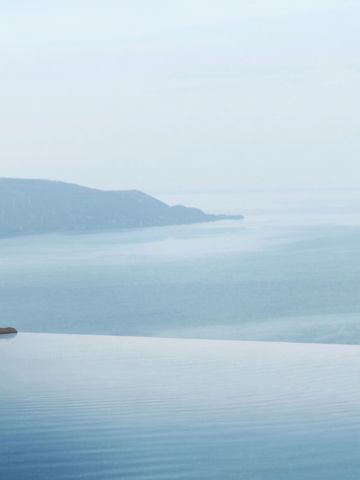 Frau entspannt im Infinity Pool mit Blick auf den Gardasee und umliegende Berge