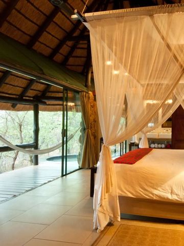 Luxuriöses Zimmer mit Baldachinbett und Aussicht in den Busch