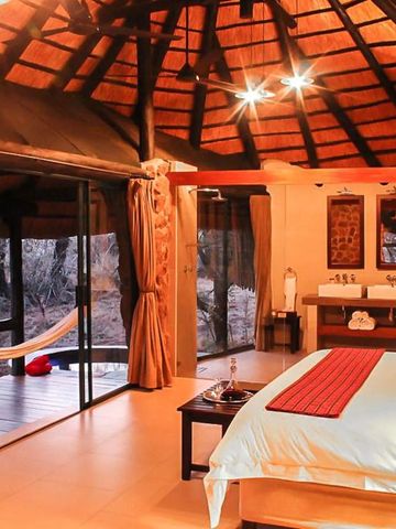 Luxuriöses Zimmer mit Reetdach und Terrasse im Safari-Stil mit Blick ins Grüne
