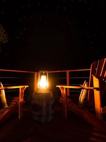 Zwei Holzstühle und eine Laterne auf einer Terrasse in der Nacht