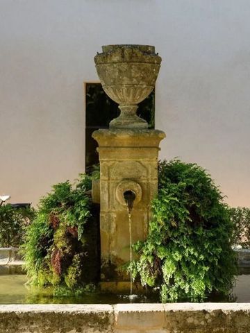 Springbrunnen in einem Garten mit üppigem Grün und antikem Steinelement