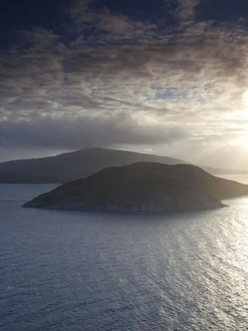 Sonnenuntergang über einer ruhigen Meereslandschaft mit Insel im Hintergrund