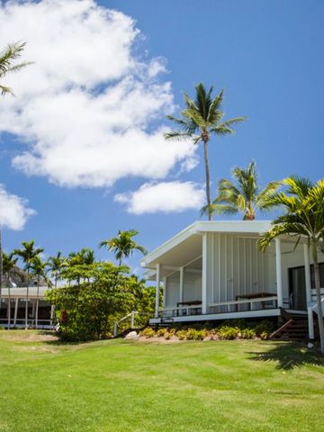 Moderne Bungalows mit Palmendach und tropischer Vegetation unter blauem Himmel