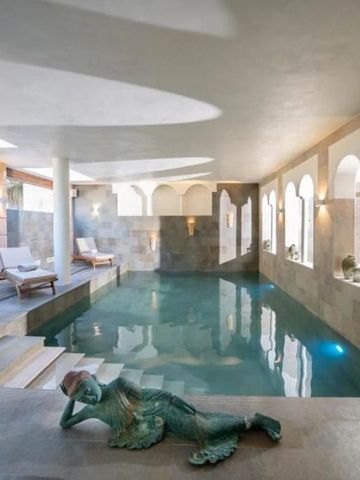 Eleganter Innenpool mit natürlichen Steinwänden und Liegestühlen
