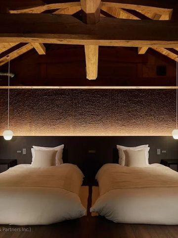 Gemütliches Hotelzimmer mit Holzbalken und indirekter Beleuchtung über den Betten