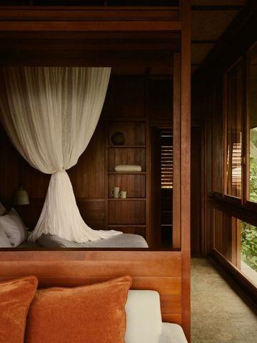 Gemütliches Zimmer mit Himmelbett und großen Fenstern zur Natur