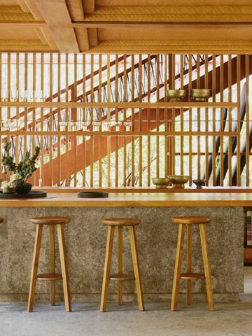 Stylische Bar mit hölzernen Hockern und dekorativer Wandverkleidung