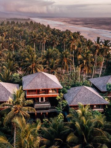 Luftaufnahme von luxuriösen Villen inmitten von Palmen am tropischen Strand
