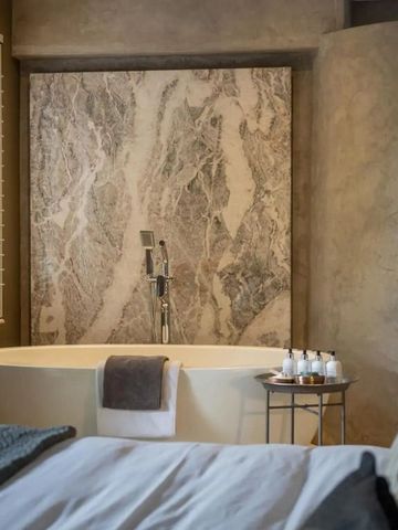Hauptschlafzimmer mit freistehender Badewanne und eleganter Marmorwand