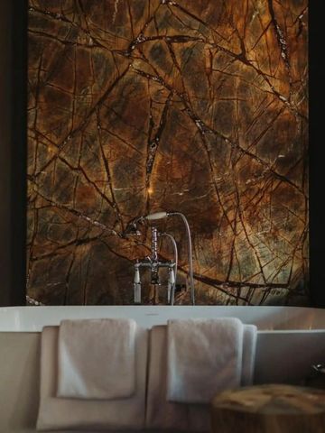 Luxuriöses Badezimmer mit freistehender Badewanne und dekorativer Steinwand