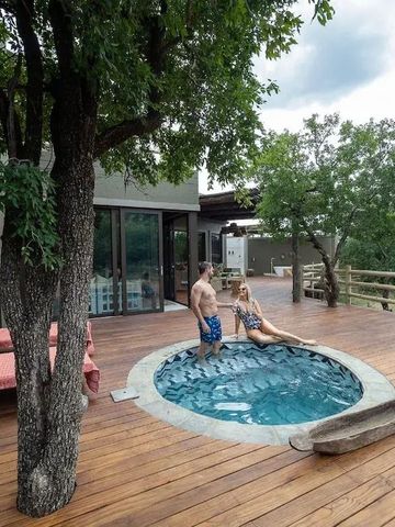 Paar in einem Whirlpool auf einer Holzterrasse mit Blick auf die Natur.