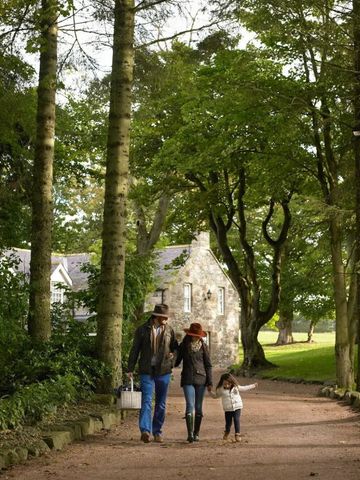 Familie spaziert durch bewaldeten Weg bei historischer Kapelle