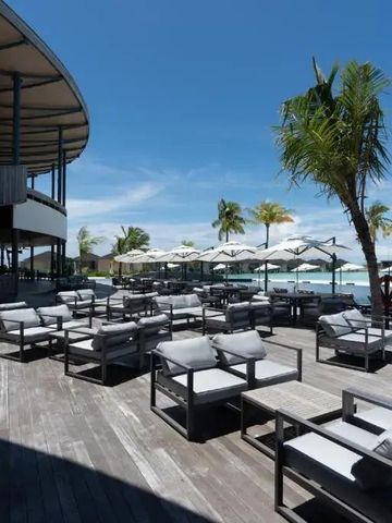 Terrasse mit Meerblick und Sitzmöbeln unter Palmen
