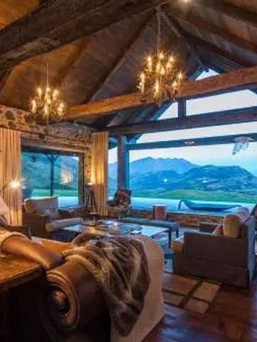 Wohnzimmer mit Holzbalkendecke und Panoramafenstern mit Bergblick