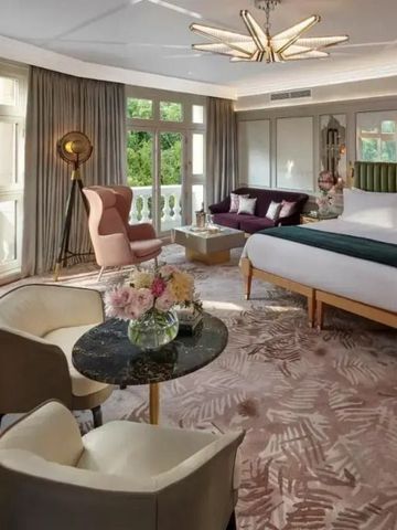 Großzügige Suite mit Kingsize-Bett, stilvollen Möbeln und Blick auf Grünanlagen.
