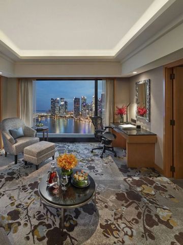 Suite mit Panoramafenster und Ausblick auf die Skyline bei Nacht.