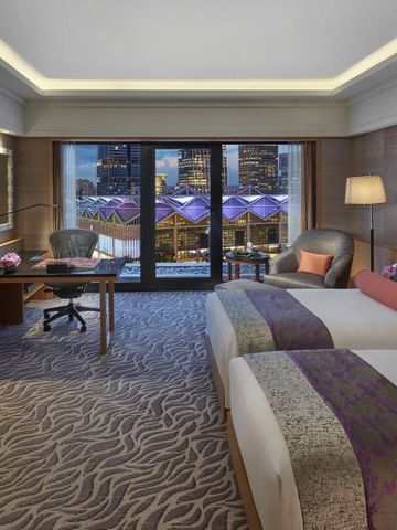 Geräumiges Hotelzimmer mit zwei Einzelbetten und Blick auf die Stadt bei Nacht
