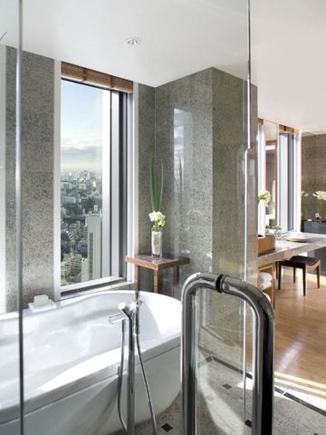 Helles Badezimmer mit freistehender Wanne und Panoramafenstern mit Stadtblick