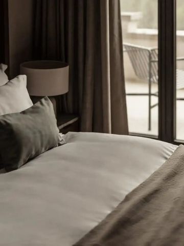 Gemütliches Hotelzimmer mit großem Bett und Terrasse im Hintergrund