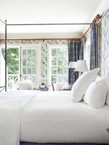 Helles Gästezimmer mit Himmelbett und großen Fenstern